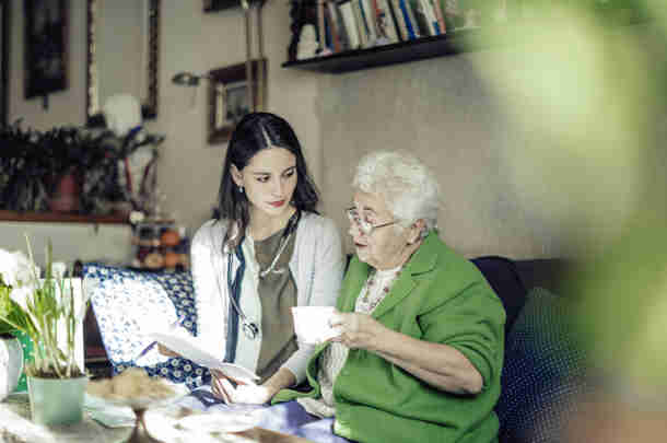 Begeleider kijkt met oudere vrouw naar administratie 