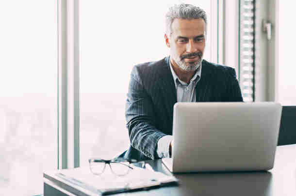 Grijze man achter laptop